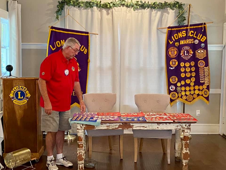 Lion Hal standing beside a table with his pin collection